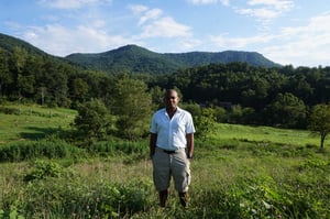 Kevin standing outdoors with view of mountain, rolling hills, and lots of green